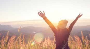 Junge Frau genießt ihre Freiheit vor einer Landschaftskulisse