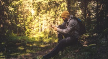 Ein Mann beim Wandern im Wald mit Smartphone