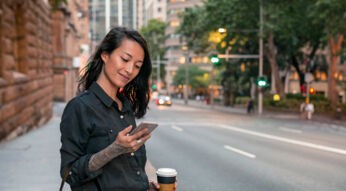 Junge Frau sieht sich auf dem Smartphone ein WhatsApp-Profilbild an.