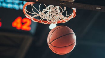 In der NBA den Basketball in den Korb werfen.