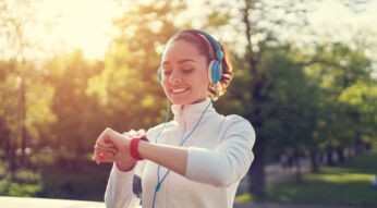 Junge Frau schaut auf ihren eingerichteten Fitbit-Tracker.