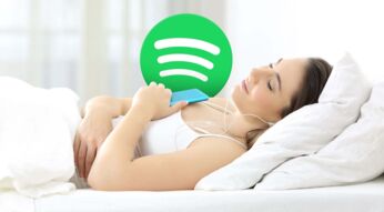 Frau liegt im Bett und hört übers Smartphone Spotify zum Einschlafen