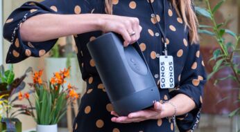 Frau hält den mit Spotify verknüpften Sonos-Lautsprecher in der Hand.