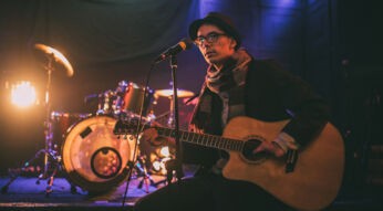 Mann mit fehlenden Finger kann durch Instrumente für Menschen mit Behinderung Gitarre spielen.