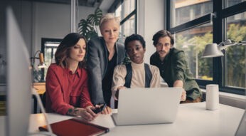 Eine Gruppe Personen arbeitet gemeinsam an einem Laptop
