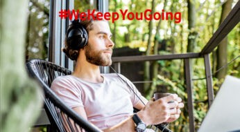 Mann mit Kaffee in der Hand hört über Kopfhörer Mindfulness-Podcasts auf dem Balkon