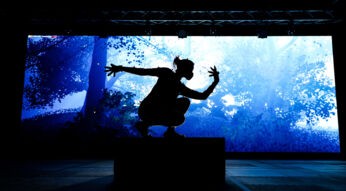 Die Silhoutte eines Schauspielers, der auf der Bühne im virtuellen Stück "Dream" performt, vor einem Wald.