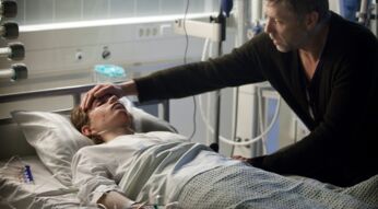 Im Krankenhaus: Ein Mann legt einer Frau die Hand auf die Stirn.