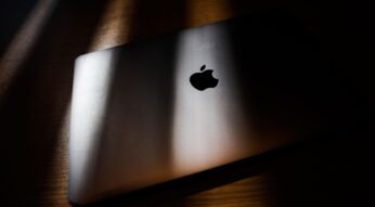 Ein MacBook Pro liegt auf einer hölzernen Oberfläche im Schatten.