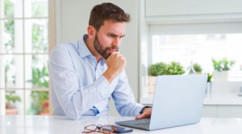 Mann sitzt konzentriert an seinem Laptop