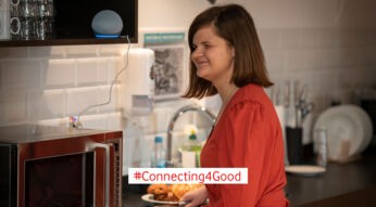 Eine Frau bereitet etwas in der Küche zu und hört einer Audiodeskription über ihr Alexa-Gerät zu.