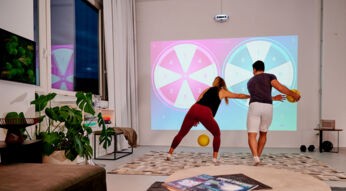 Eine Frau und ein Mann spielen ein Ballspiel mit der Fitness-Konsole Limbic Active gegeneinander, indem sie die Bälle an die Wand schmeißen.