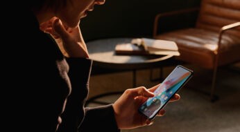 FRau hält Oppo Find X3 Pro vor Ledersessel