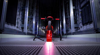 Ein rotes Fahrrad mit Stützrädern, davor ein Smartphone, das "5G Standalone" auf dem Display zeigt.