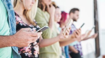 Junge Leute halten Handys in den Händen.