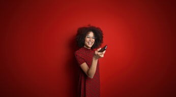 Eine Frau hält eine Fernbedienung und schaltet damit um.