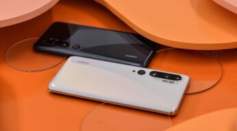 Zwei Xiaomi-Smartphones liegen auf orangefarbenem Untergrund