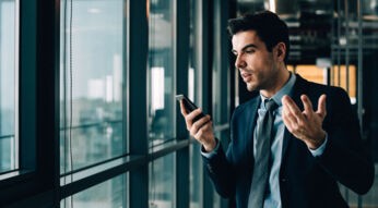 Mann schaut genervt auf sein Smartphone, weil Android-Apps ständig abstürzen.