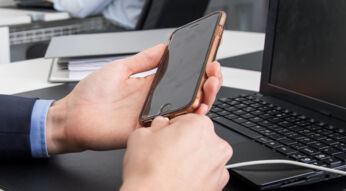 Mann schließt sein iPhone ans Ladekabel an, da der Akku leer ist.