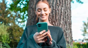 Junge Frau schaut auf ihr Smartphone.
