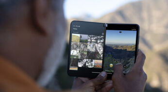 Mann hält Falt-Smartphone Surface Duo 2 vor Berglandschaft
