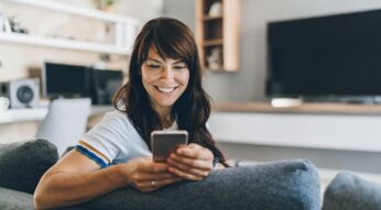 Frau schaut lächelnd auf ihr Handy.