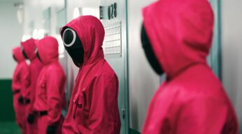 Mehrere Personen in roten Overalls stehen vor einer Wand