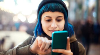 Eine junge Frau tippt auf ihrem Smartphone.