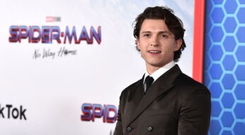 Tom Holland beste Filme – auf diesem Bild ist Tom Holland bei der Premiere von Spider-Man: No Way Home zu sehen. Er trägt einen eleganten, dunkelbraunen Anzug mit schwarzer Krawatte und blickt leicht lächelnd in die Kamera.