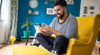 Mann schaut lächelnd auf sein Android-Smartphone.