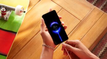 Hand hält ladendes Xiaomi-Smartphone über Holztisch