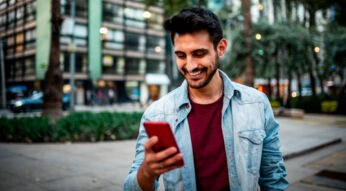 Mann ist unterwegs in der Stadt und freut sich über iPhone-Tricks.