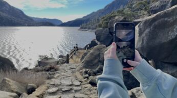 Zwei Hände halten iPhone zum Fotografieren eines Sees im Yosemite Nationalpark