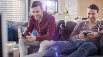 Zwei Männer spielen an der PlayStation.