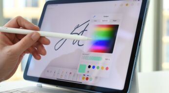 Frauenhand führt Stift auf einem iPad und wählt aus Farbpalette aus