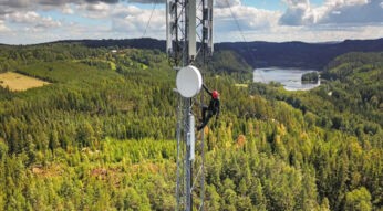 Ein Mensch klettern auf einem Sendemast innmitten eines Waldes.