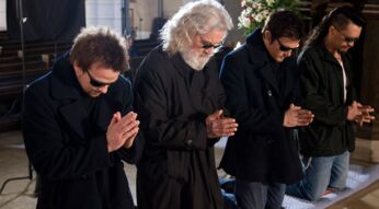 Vier Männer in Schwarz knien und beten in einer Kirche