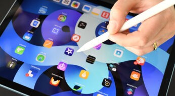 Hand mit Apple Pencil über einem iPad Air mit zahlreichen App-Symbolen