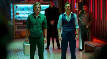 Zwei Männer stehen mit einem Koffer in einem Bahnhof