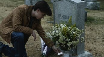 Ein junger Mann kniet an einem Grab