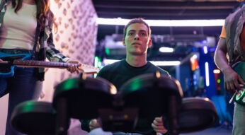 Ein junger Mann spielt mit dem Schlagzeug das Spiel Rock Band