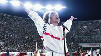 Eine Sängerin performt in einem vollen Stadion.
