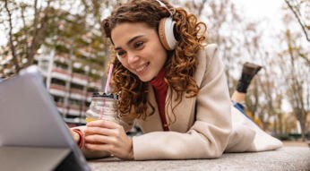 Junge Frau hört ein Hörbuch beim Browsen auf ihrem iPad