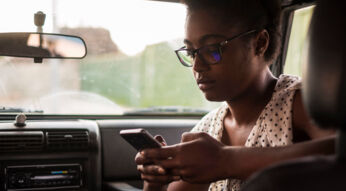Junge Frau tippt im Auto auf ihrem Galaxy-Smartphone