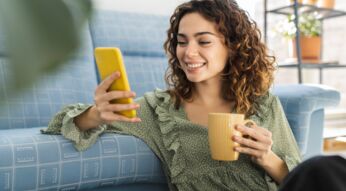 Junge FRau mit Handy auf der Couch