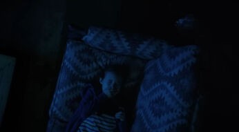 Kind liegt auf einem Sofa und hält sich den Mund zu