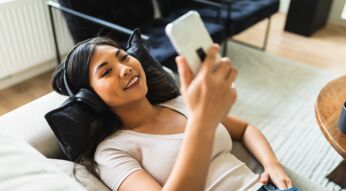 Eine junge Frau mit Kopfhörern und Smartphone hört Musik.