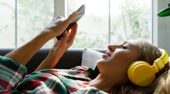 Spotify-Playlist exportieren: Frau mit Smartphone hört Musik.