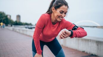Frau schaut auf ihre Smartwatch beim Sport