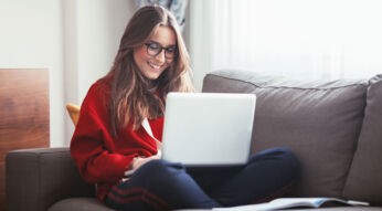 Studentin auf dem Sofa an ihrem Laptop beim Lernen